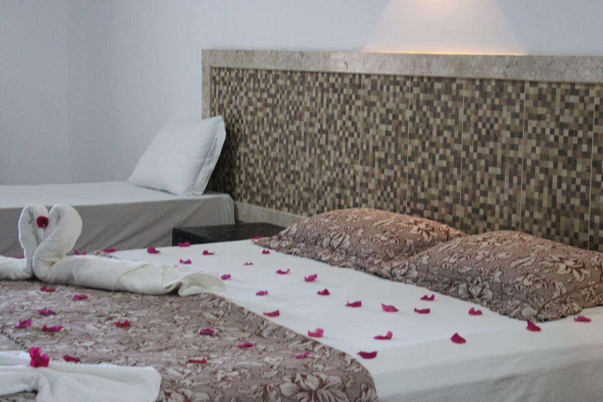 A hotel room with a bed, a headboard, and a pillow.