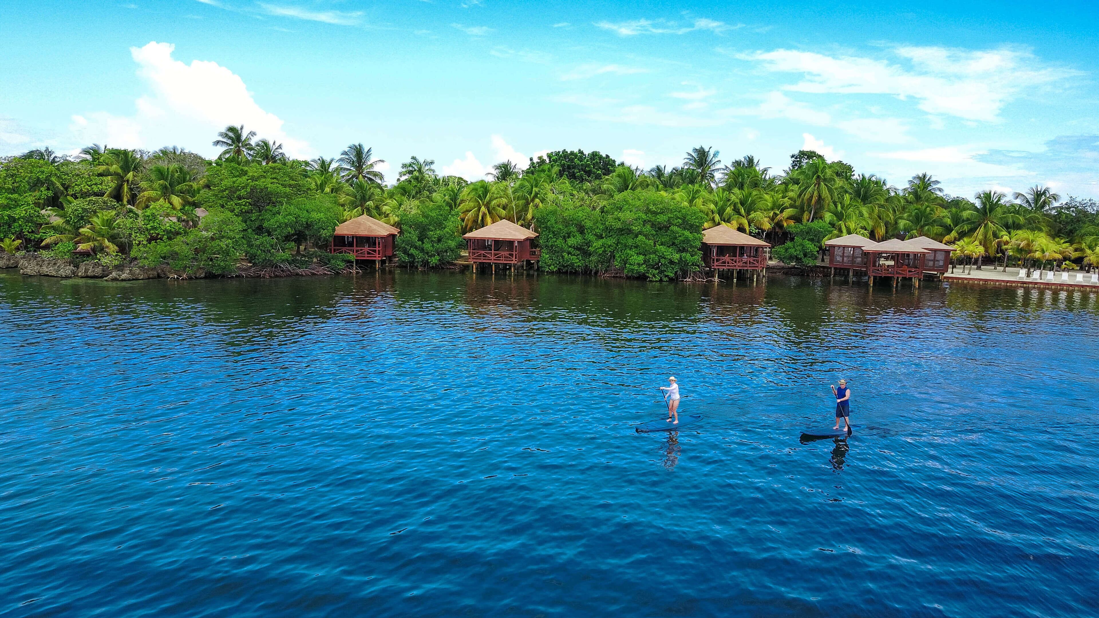 Un resort tropical con bungalows sobre el agua y una laguna azul cristalina.