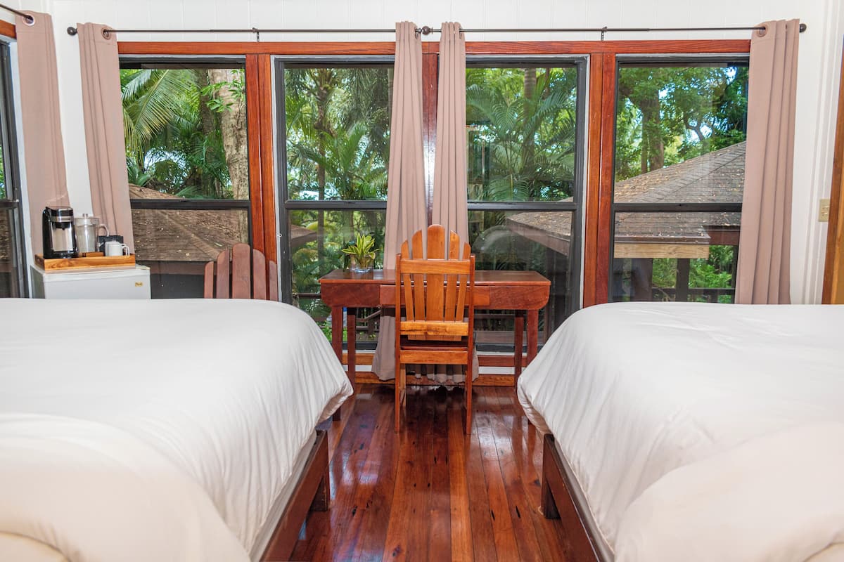 A room with two beds, a wooden table, and a chair.