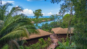 A tropical resort with a wooden deck, lush greenery, and a view of the ocean. - Anthony's Key Resort (Roatan)