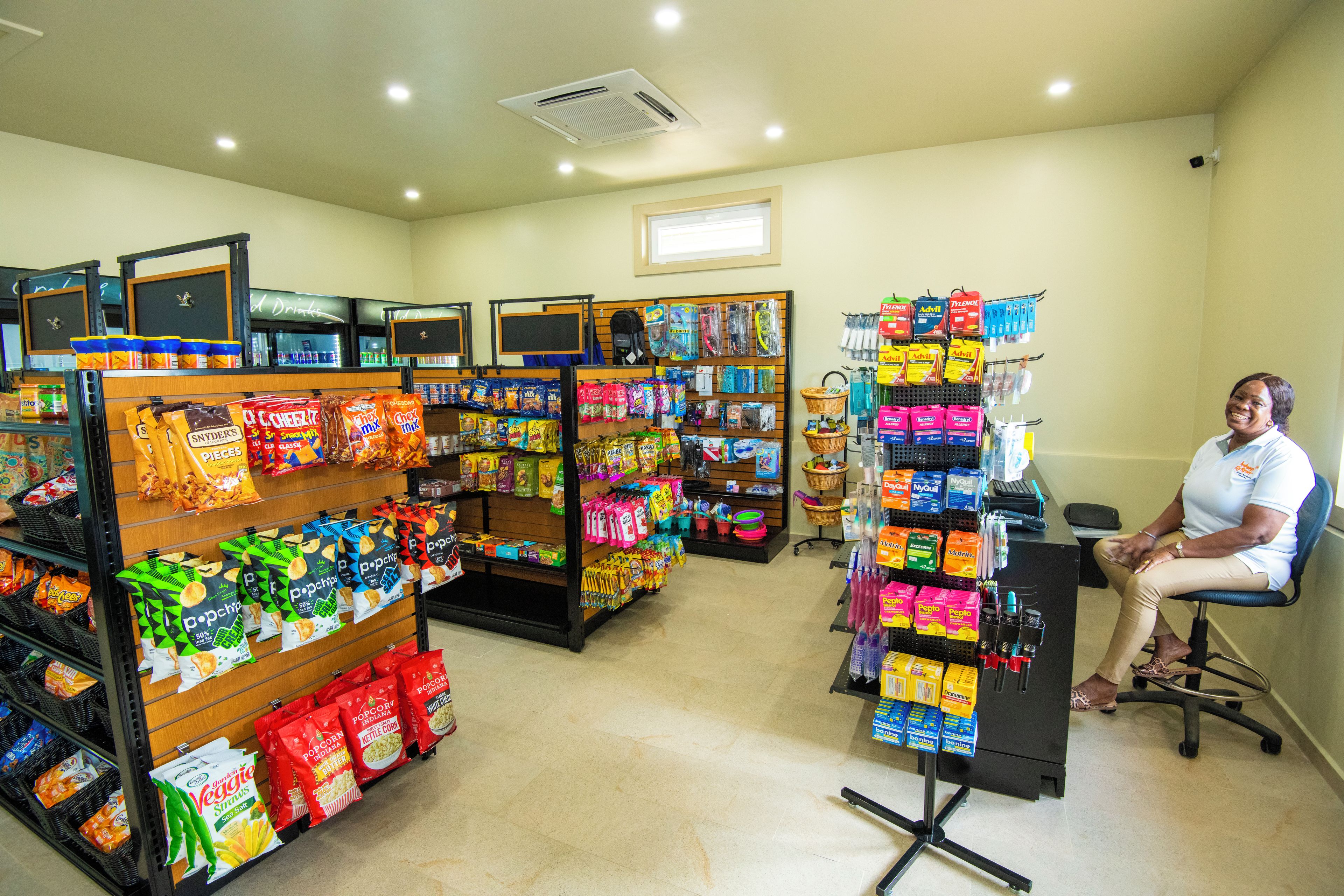 A grocery store with various snack aisles and a woman seated at a counter.