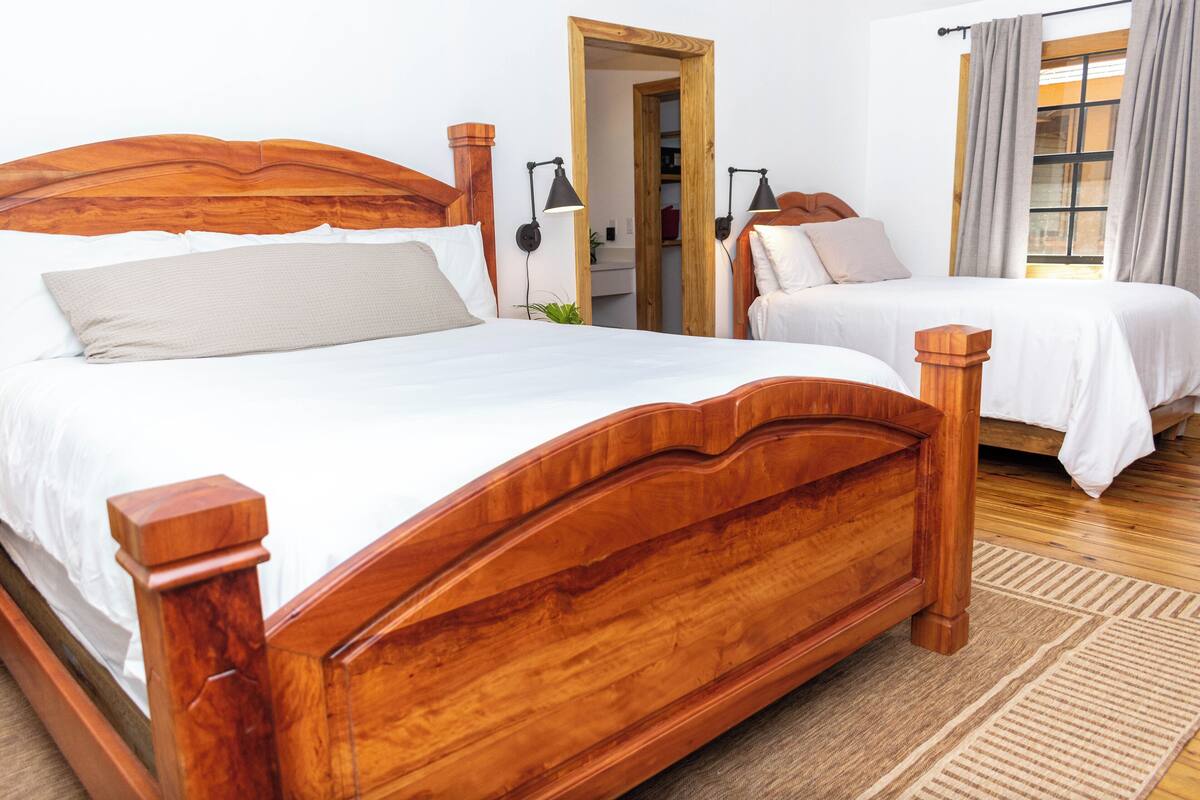 A double bed with a wooden headboard and footboard, a bedside table, and a nightstand with a lamp.