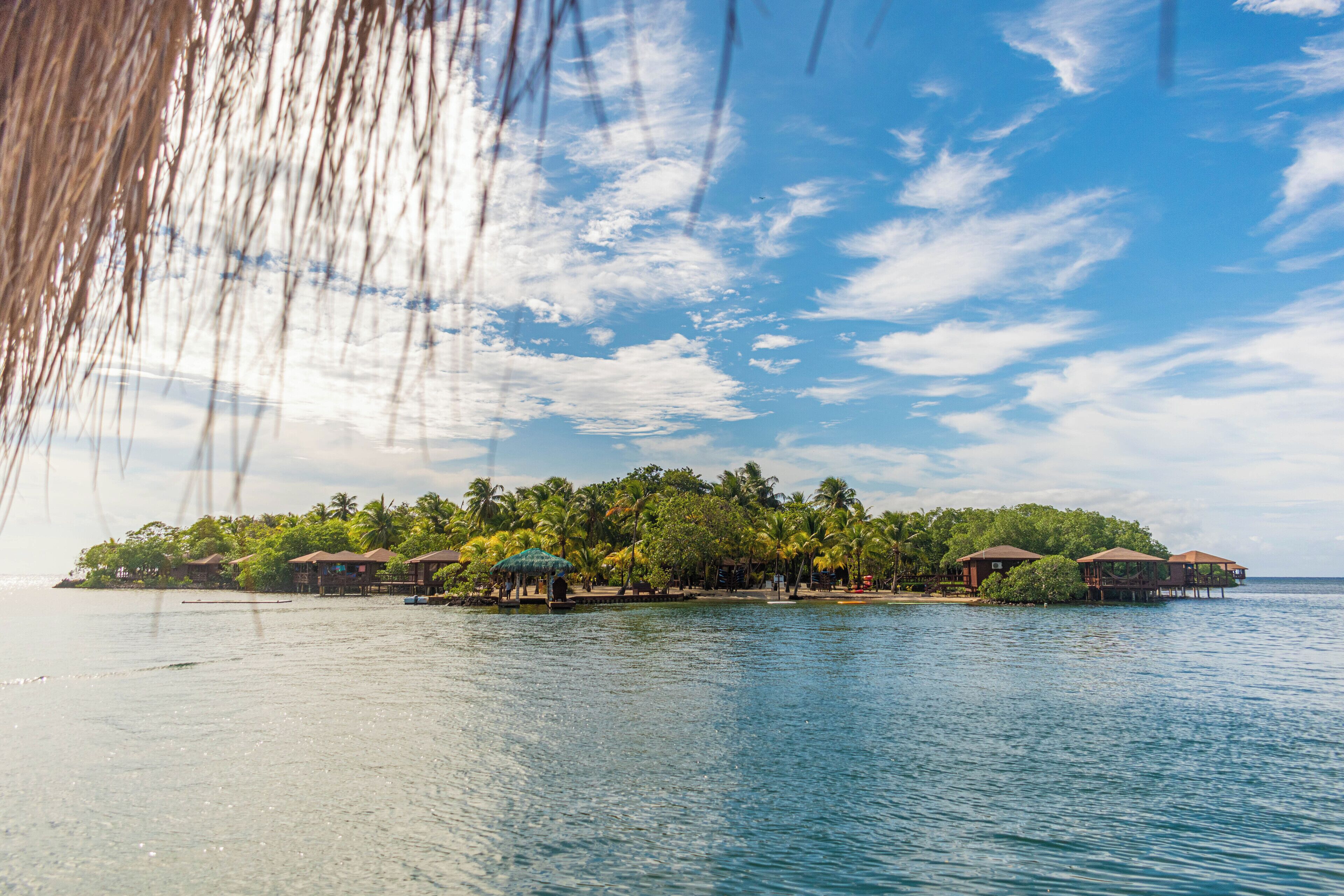 Une île tropicale dotée de bungalows sur pilotis et de palmiers.