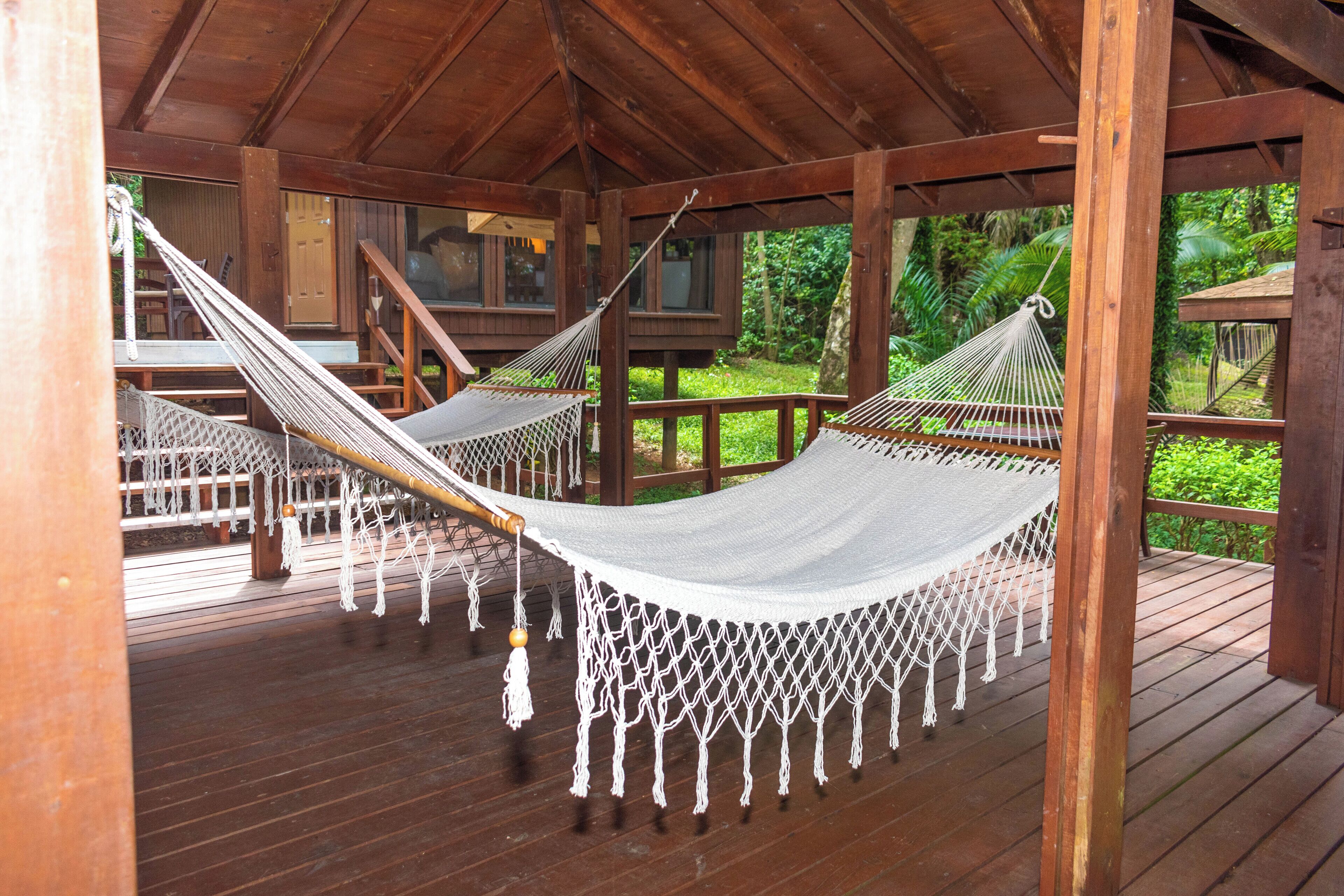 A wooden deck with two hammocks and a staircase leading to an upper level.