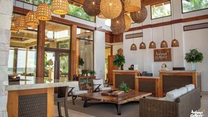 A spacious lobby with a reception desk, wicker furniture, and large windows offering views of the outdoors. - Anthony's Key Resort (Roatan)