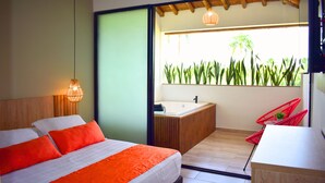 Quarto de hotel moderno com uma cama grande, um banheiro pequeno com banheira e uma varanda com plantas.