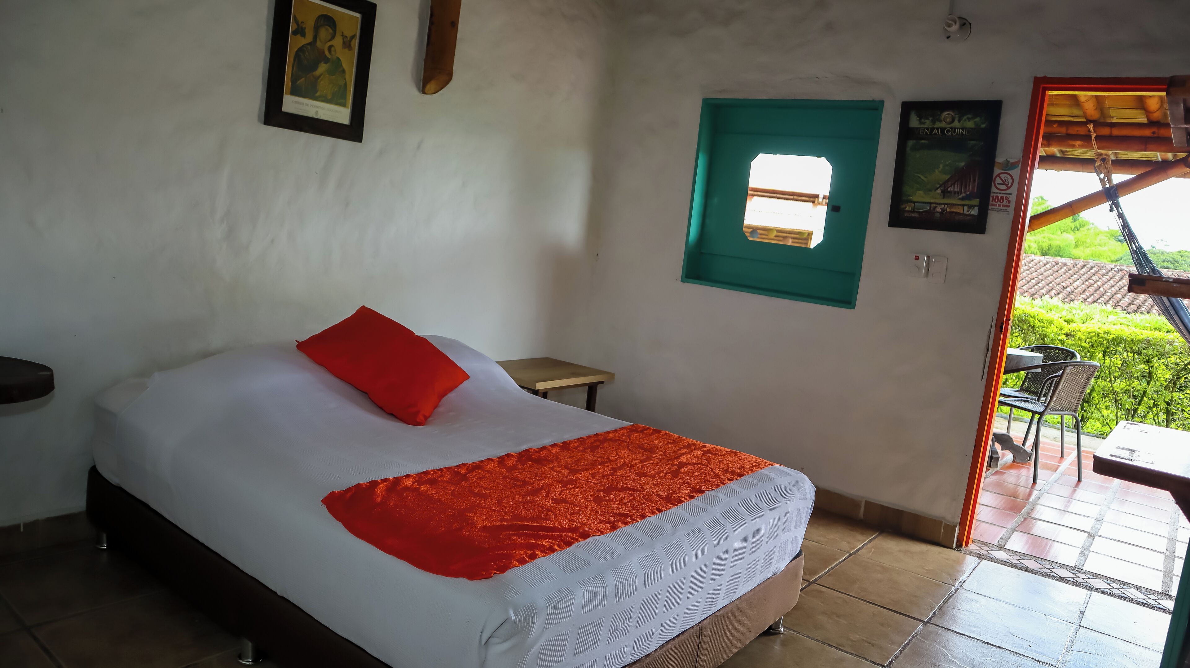 A bedroom with a bed, a red pillow, a window, and a door leading to a balcony.