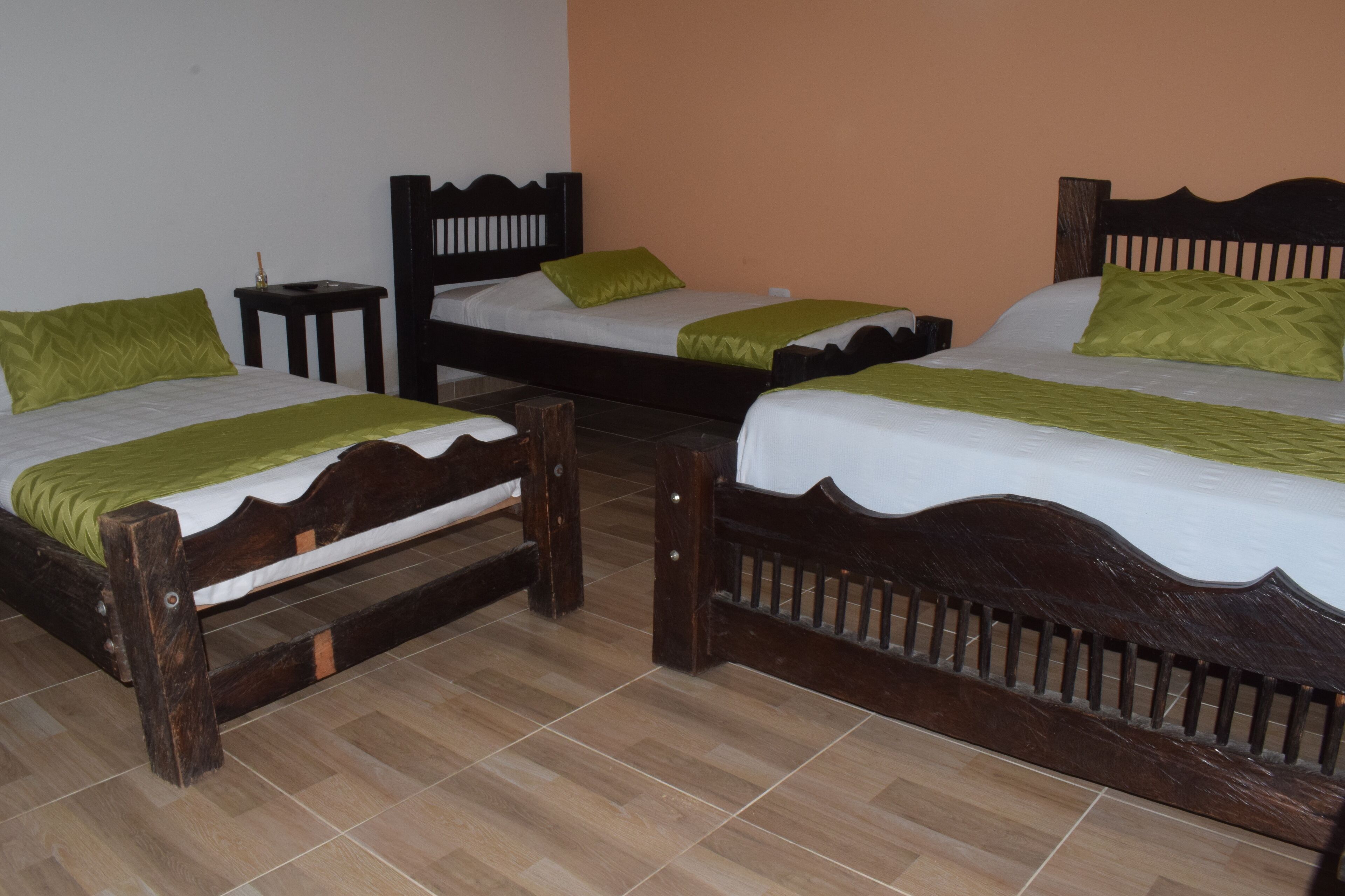 A hotel room with two wooden beds, each with a green pillow and a white bedspread.