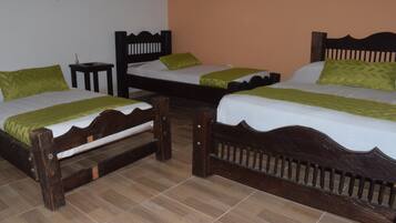 A hotel room with two wooden beds, each with a green pillow and a white bedspread.