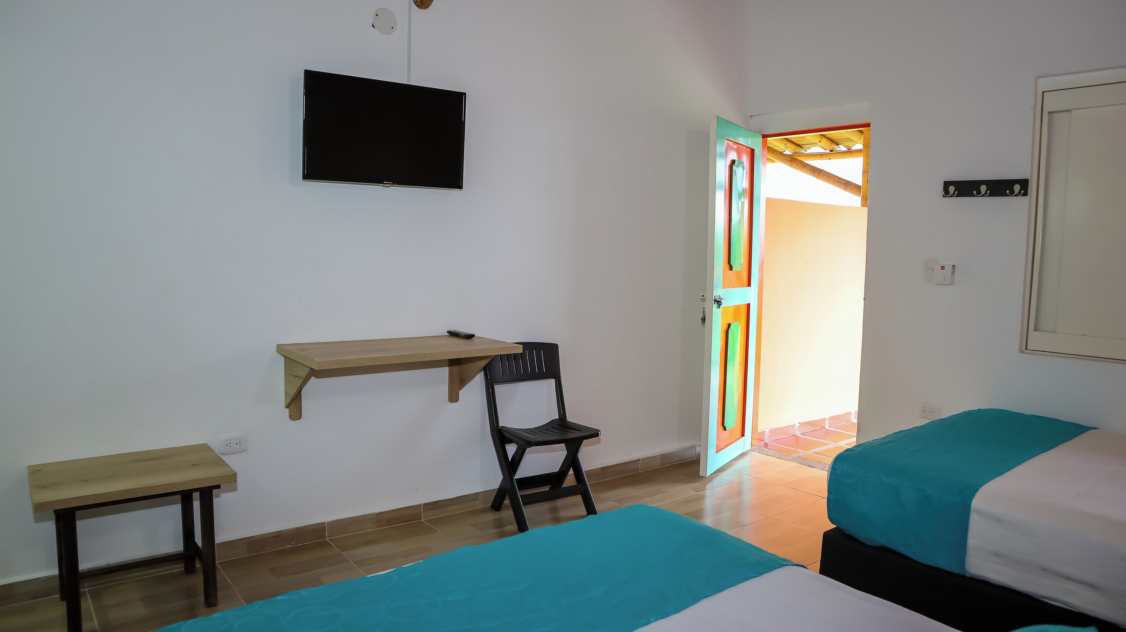 Una habitación con una cama, un escritorio, una silla y un televisor.