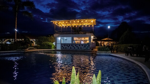 Um bar à beira da piscina com chão de azulejos, piscina e um edifício com varanda.