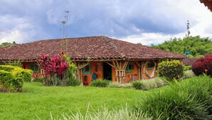 Uma casa tradicional com telhado de telhas, rodeada por vegetação exuberante e uma antena parabólica.