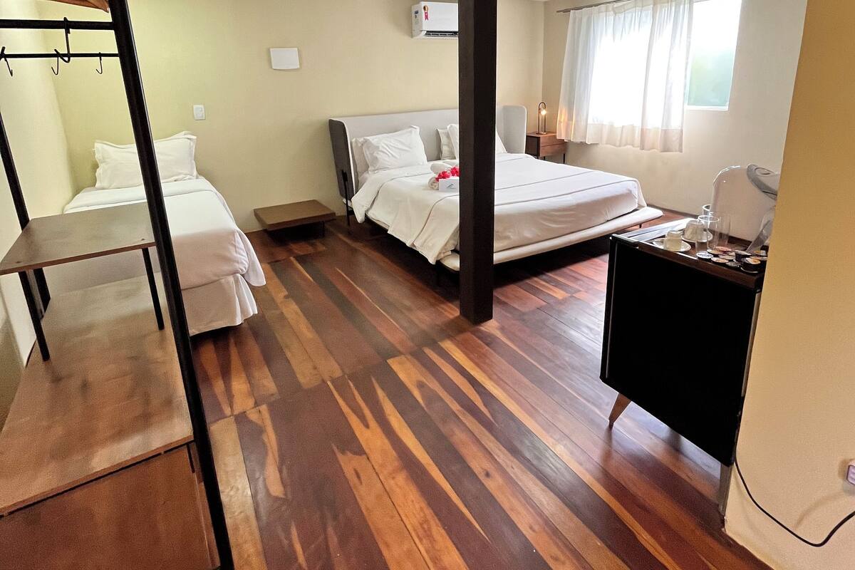 A hotel room with a bunk bed, a desk, a chair, and a window with curtains.