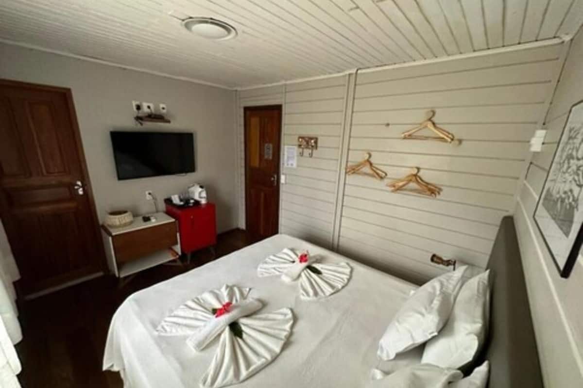 A hotel room with a bed, a TV, a desk, and a wardrobe.