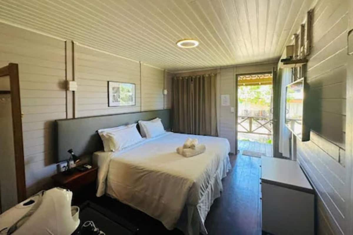 A hotel room with a bed, bedside table, and a small desk.