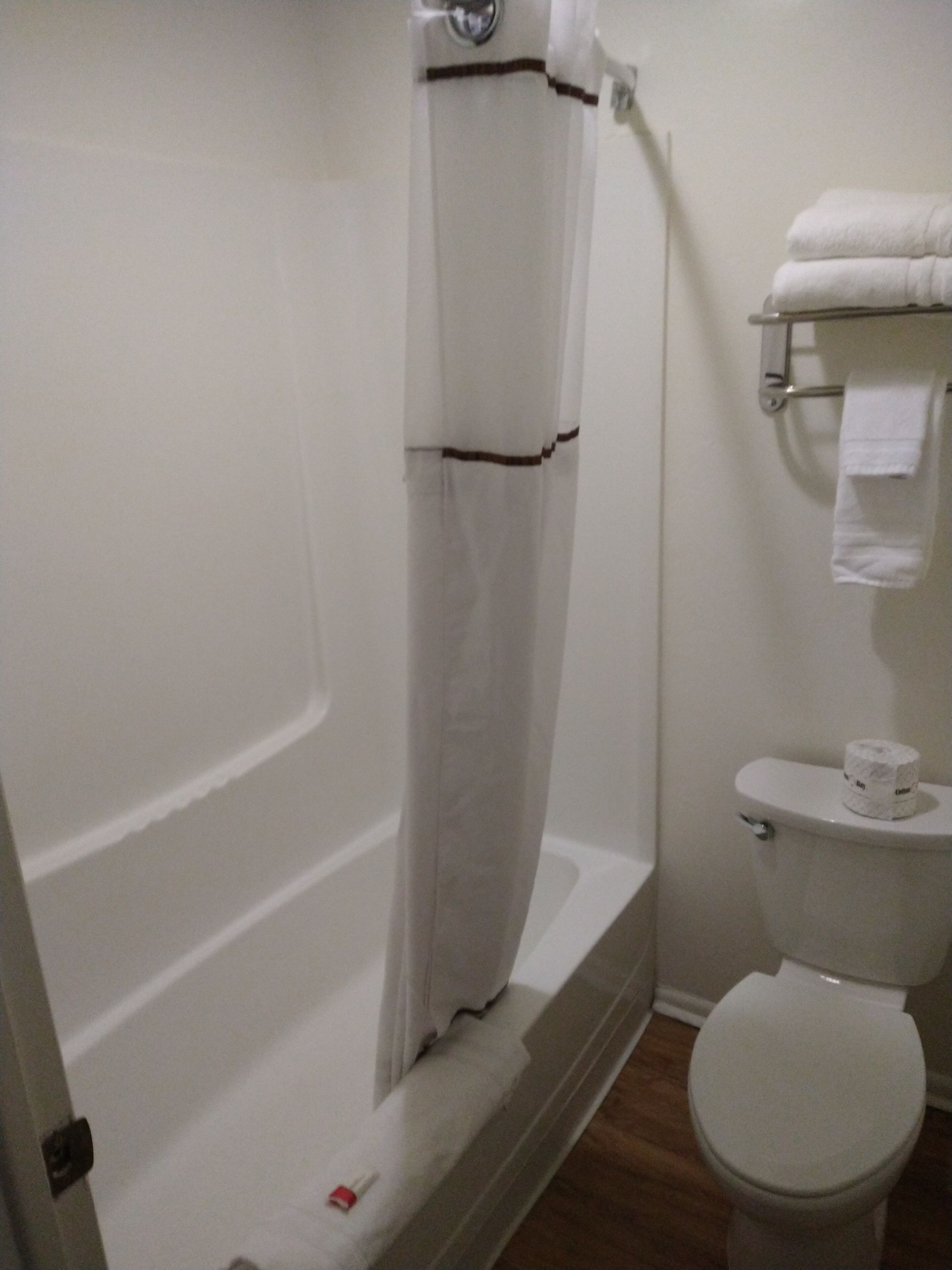 A bathroom with a bathtub, toilet, and a towel rack.