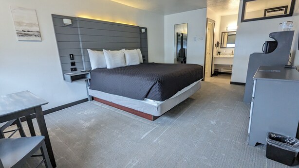 A modern hotel room with a bed, bedside table, and a small desk.