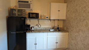 A compact kitchen with a black refrigerator, a microwave, a coffee maker, and a sink.