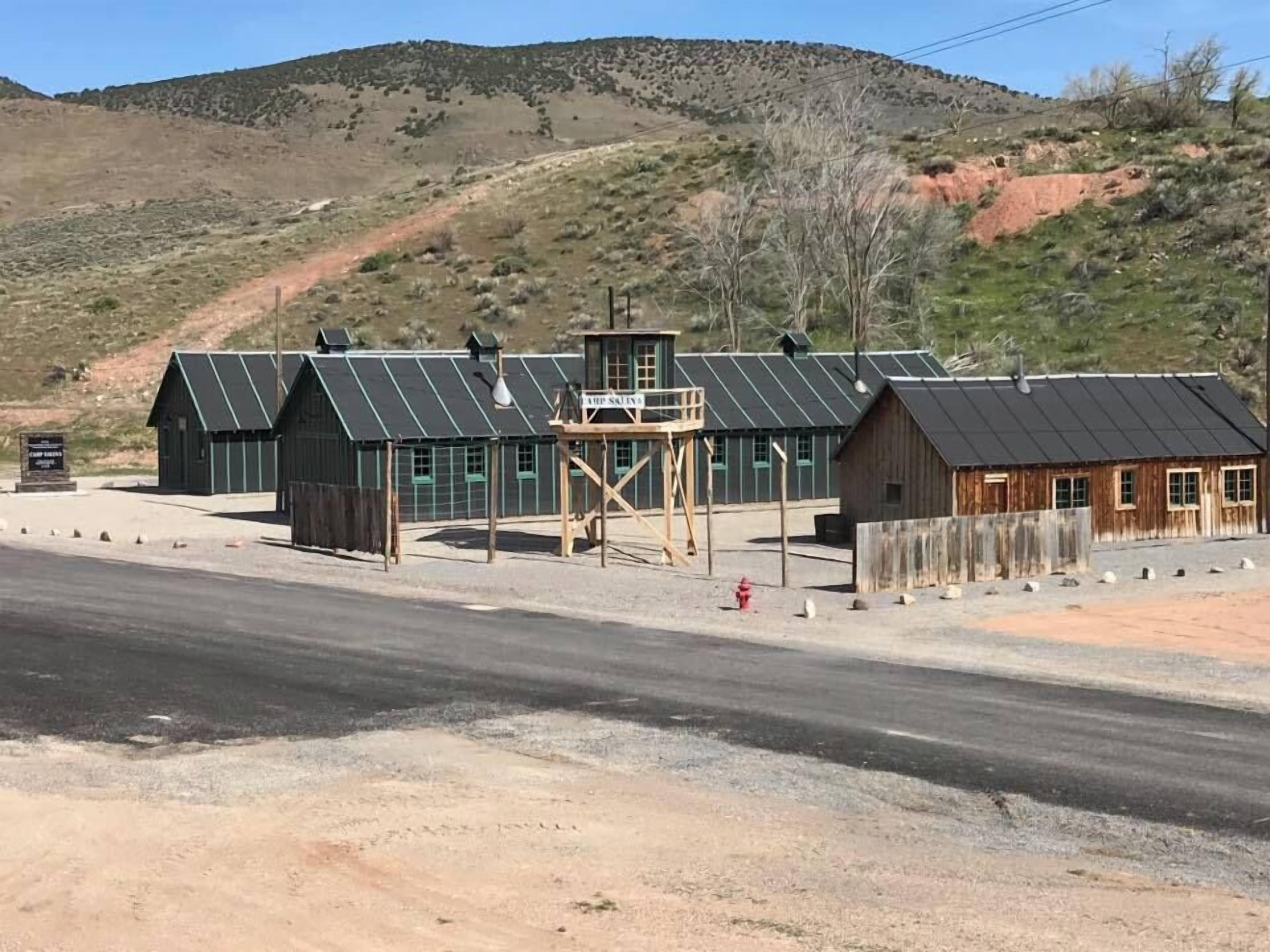 A rustic building with a metal roof and wooden structure, located near a road with a guardrail.