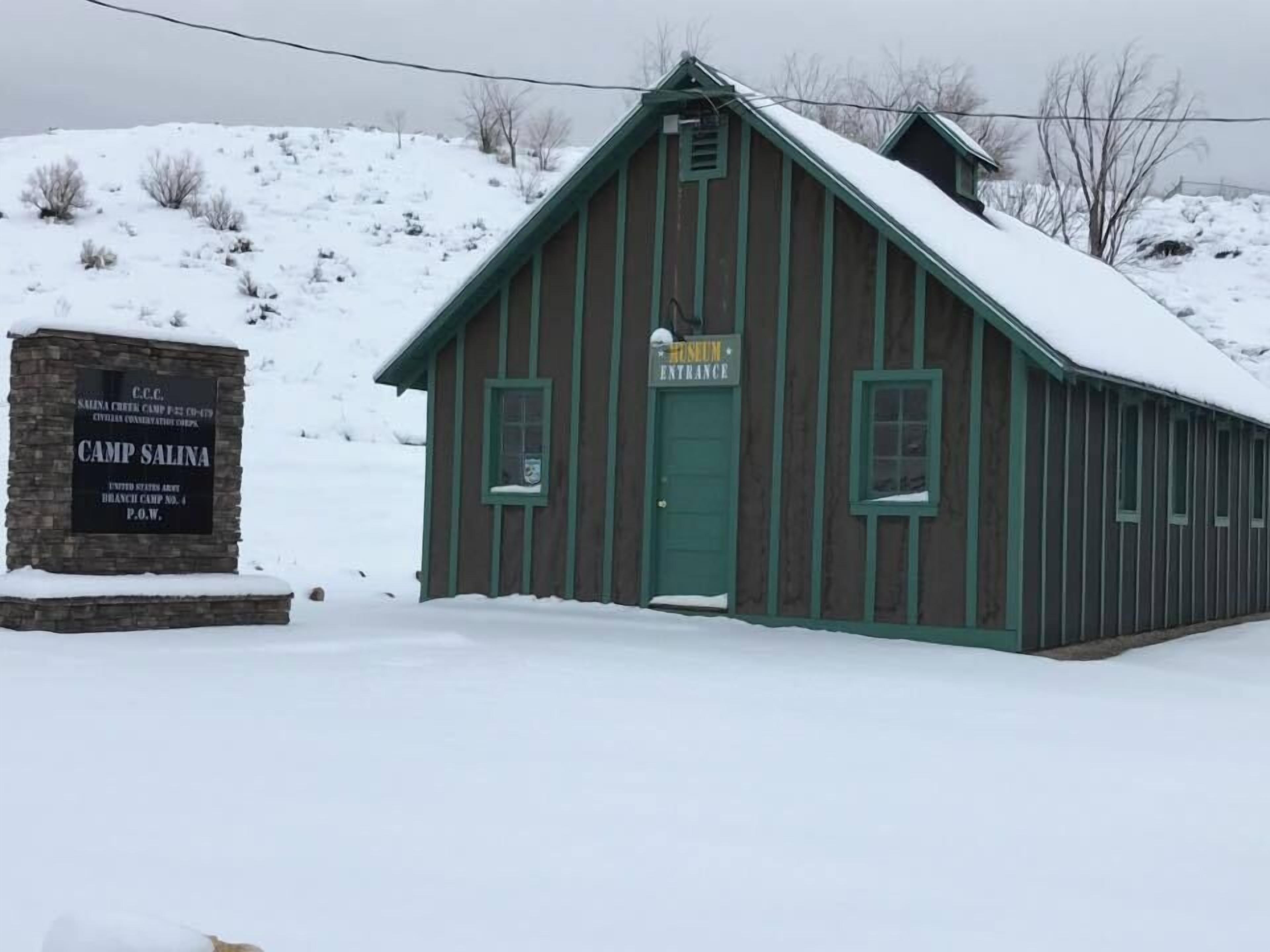 A wooden building with a green door and windows, labeled as 'Camp Salina' and 'Museum Entrance'.