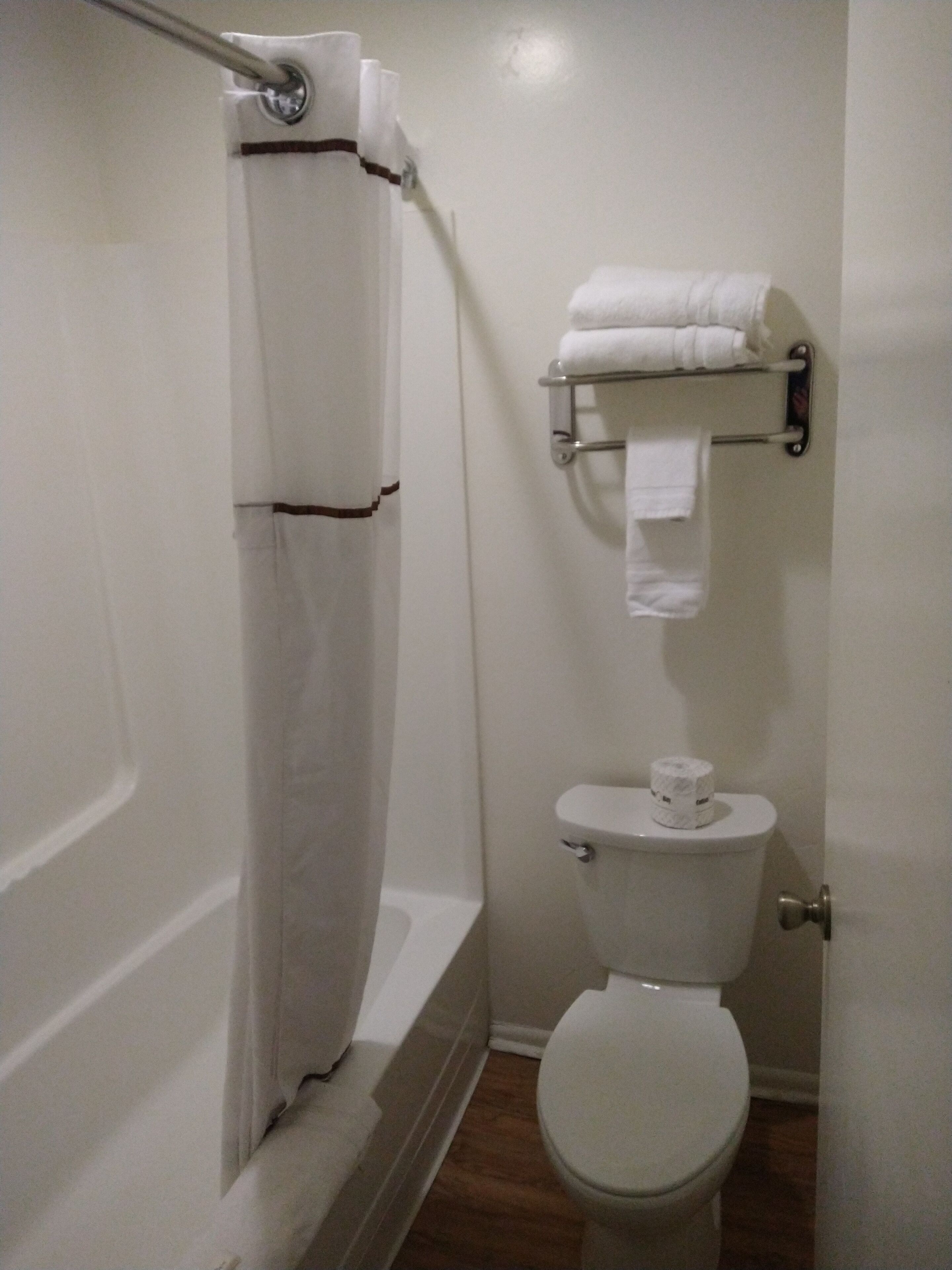 A small, clean bathroom with a toilet, a shower curtain, and a towel rack.