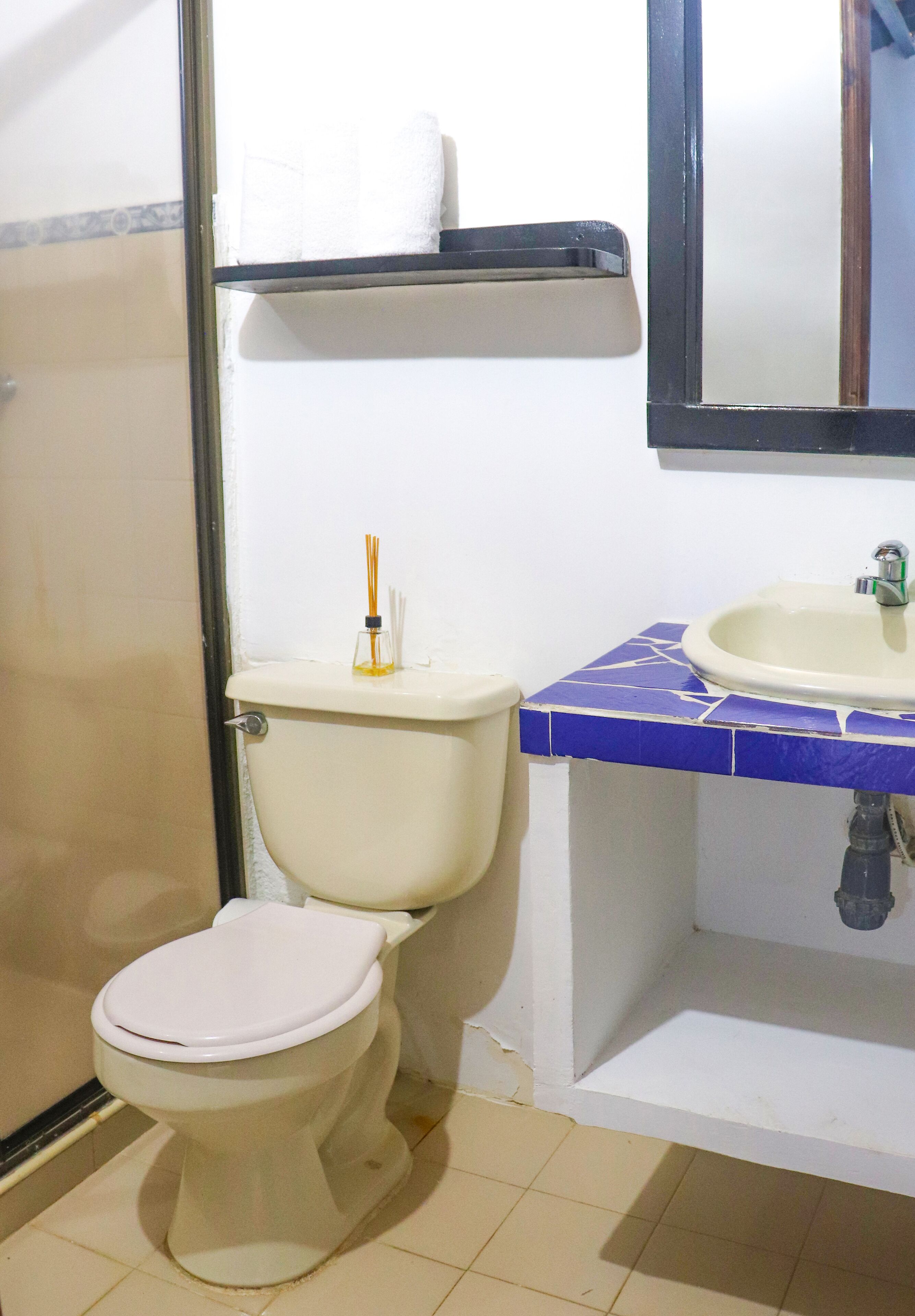 A bathroom with a toilet, sink, and mirror.