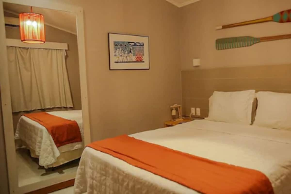 A hotel room with a bed, a nightstand, a mirror, and a painting on the wall.