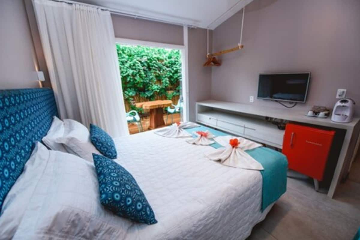 A hotel room with a bed, a TV, a desk, and a red cabinet.