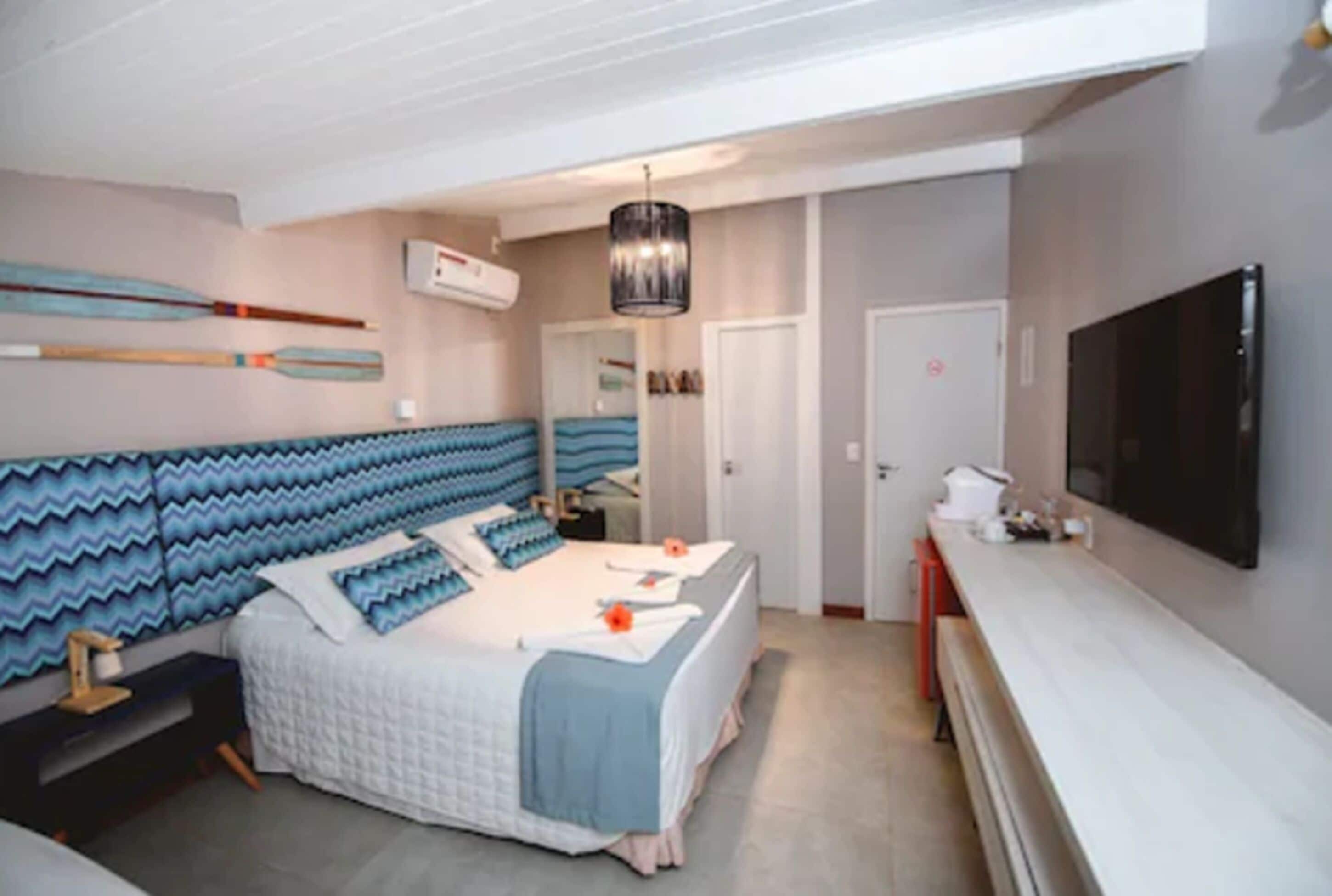 Quarto com cama, televisão e escrivaninha.