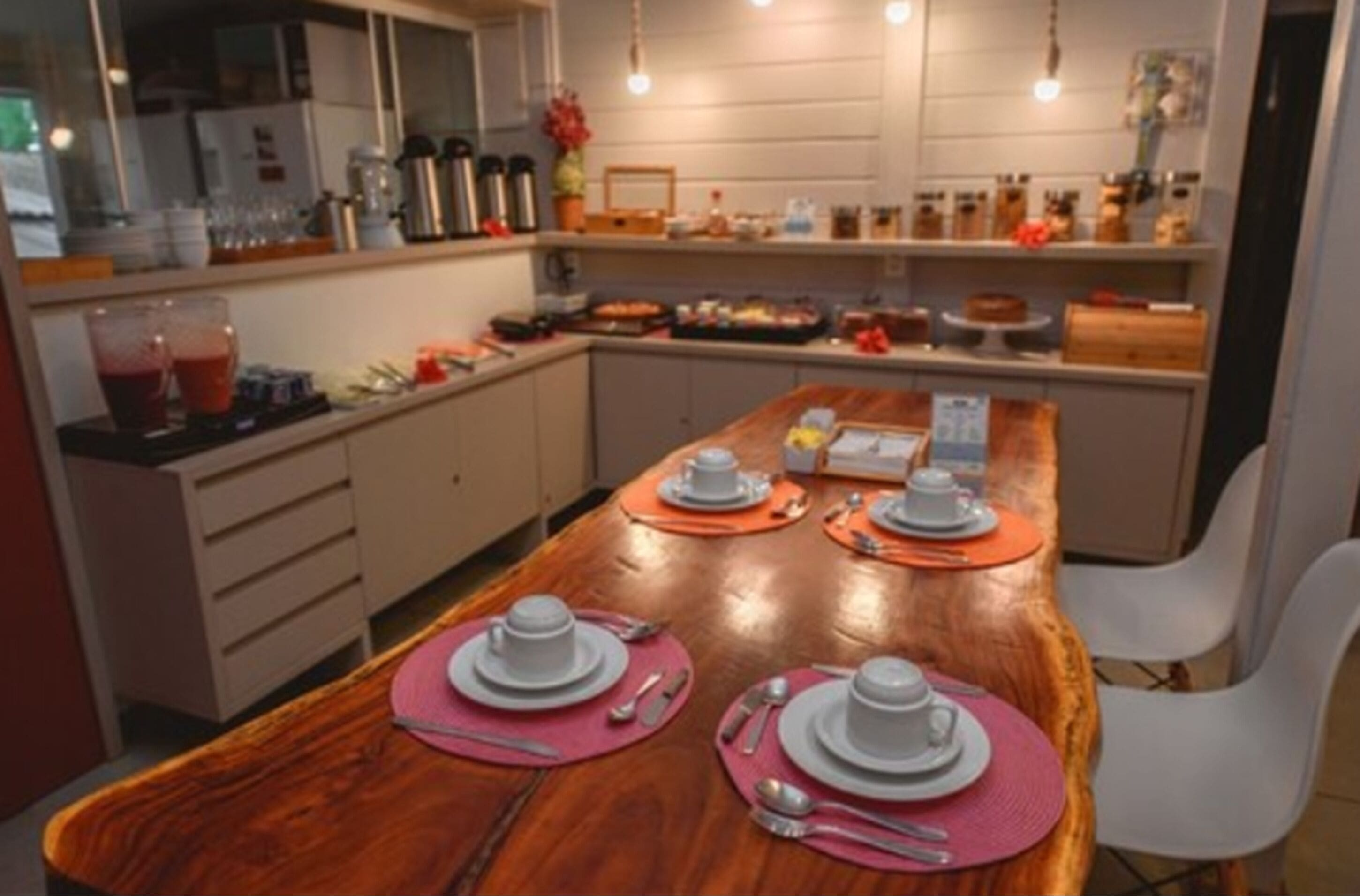 Una cocina moderna con encimeras de madera, una isla central con un lavamanos y un comedor con una mesa de madera para cuatro personas.