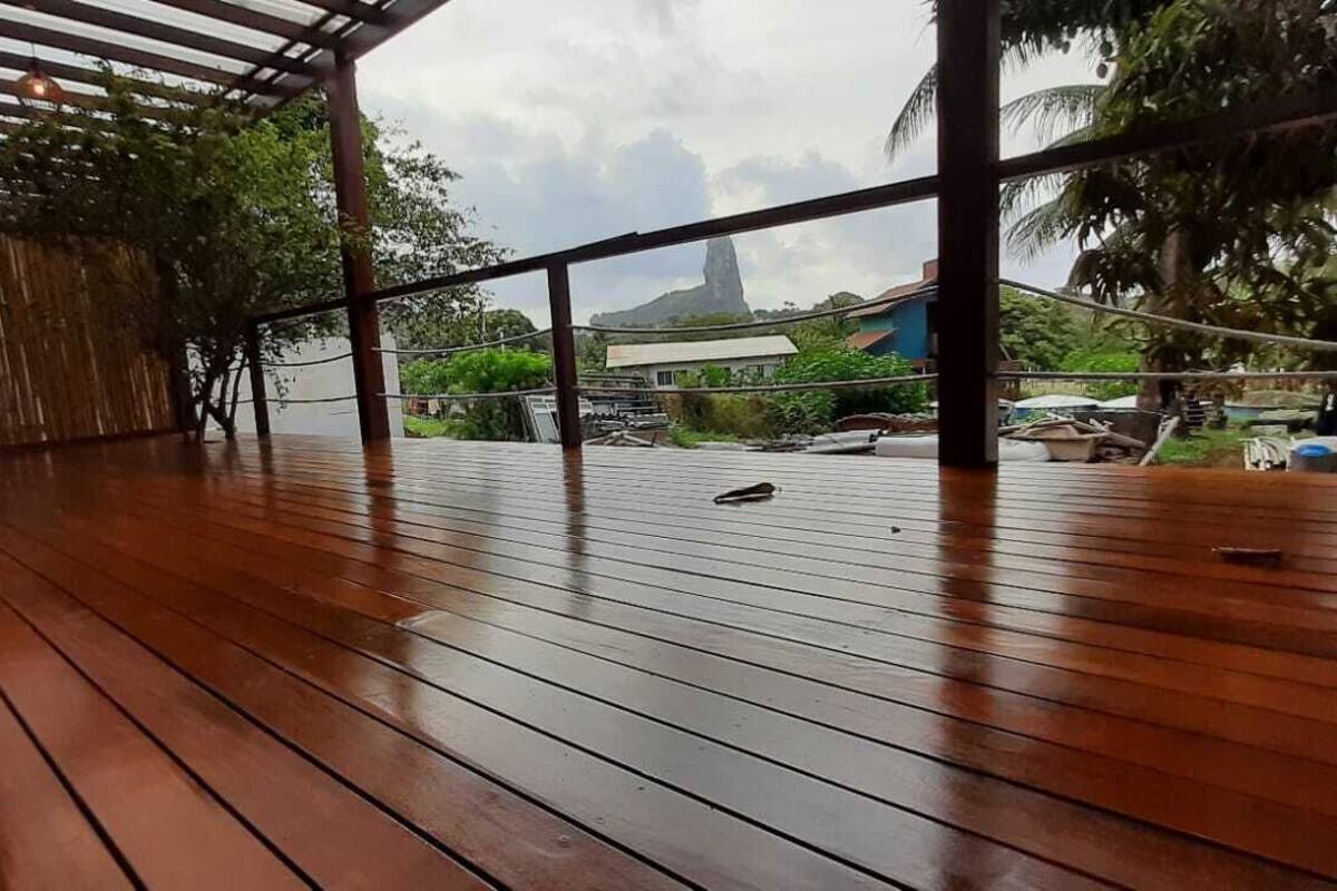 Um deck de madeira com vista para uma montanha e uma casa.
