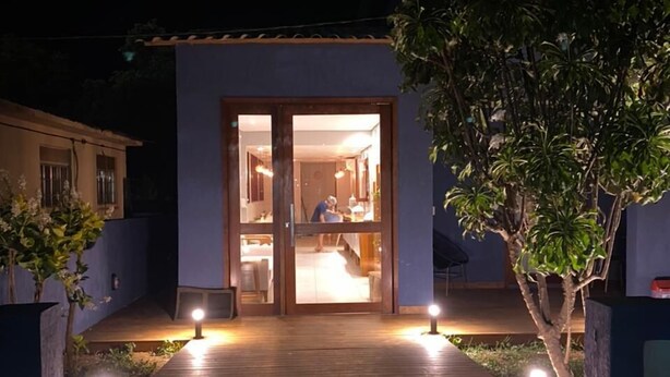 A pathway leading to a house with a glass door, surrounded by plants and illuminated by ground lights. - Pousada da Mana (Fernando de Noronha)