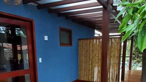 A spacious room with a wooden floor, a glass door, and a ceiling with a wooden beam structure. - Pousada da Mana (Fernando de Noronha)