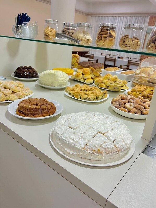 Un buffet proposant une variété de desserts et de pâtisseries, notamment des gâteaux, des biscuits et des viennoiseries, présentés sur un comptoir en verre.