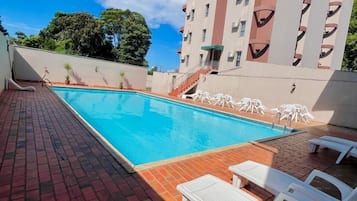 Una piscina al aire libre, sillones reclinables de piscina