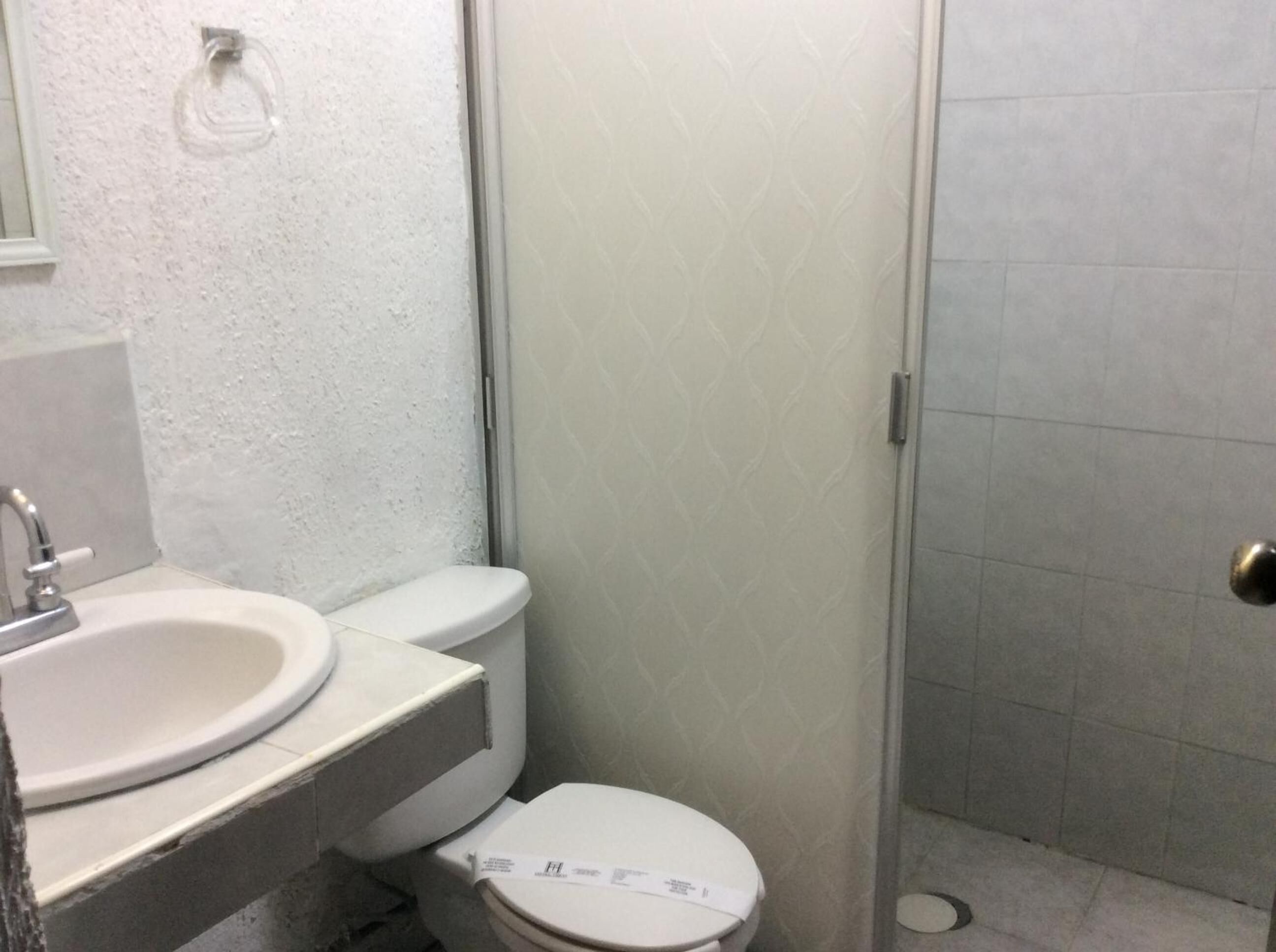 Un baño con lavamanos, inodoro y zona de ducha blancos.