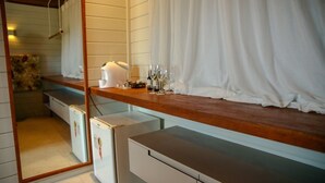 A compact kitchen with a wooden countertop, a white refrigerator, and a mirror reflecting the room. - Pousada Nascer do Sol (Fernando de Noronha)