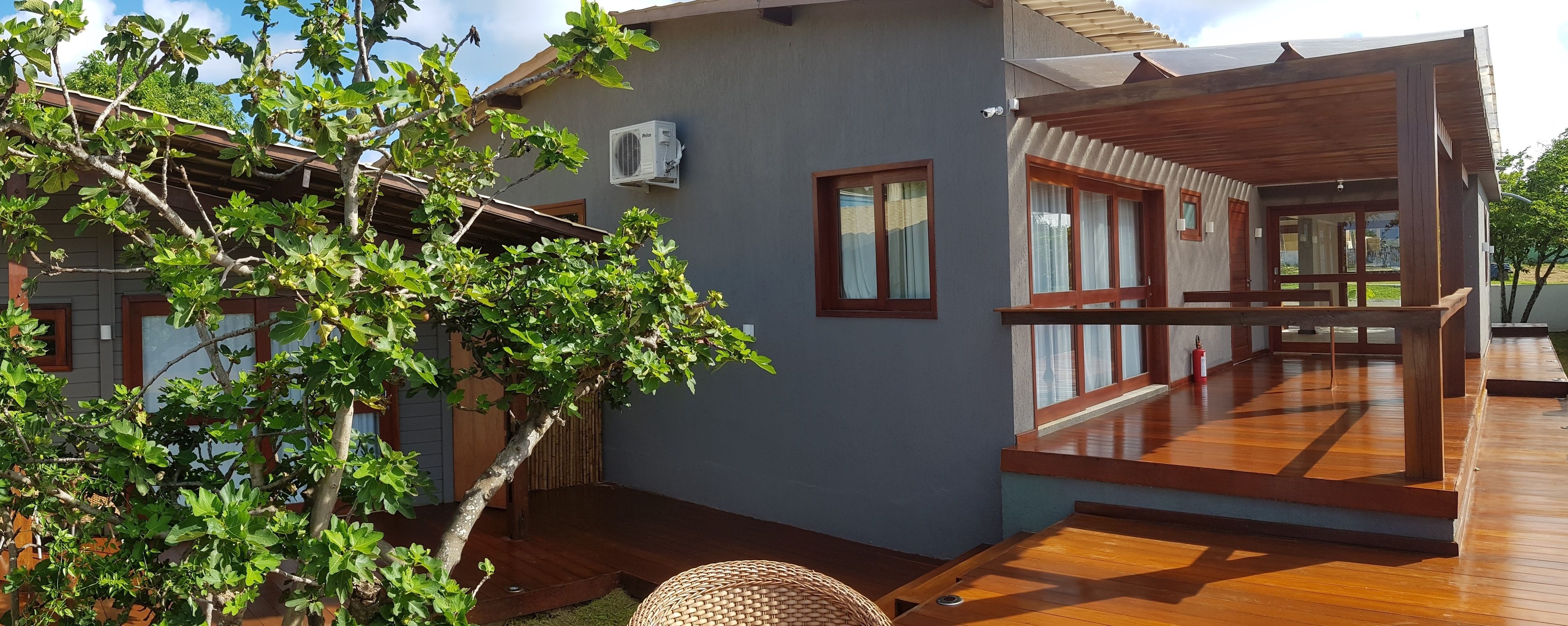 A modern house with a wooden deck, a small garden, and a window with a curtain.