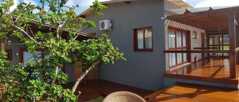 A modern house with a wooden deck, a small garden, and a window with a curtain.