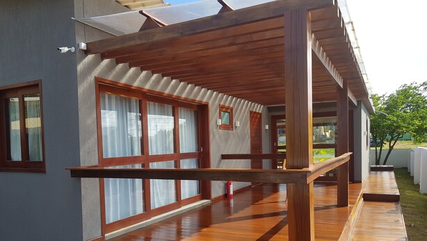 A modern building with large windows, wooden deck, and a covered outdoor area. - Pousada Nascer do Sol (Fernando de Noronha)