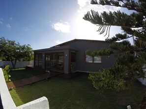 Una casa moderna con un amplio acceso por puerta de vidrio, un pequeño patio y un césped bien cuidado.