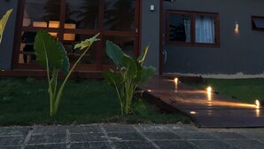 A modern house with large glass doors, a small porch, and a well-maintained lawn. - Pousada Nascer do Sol (Fernando de Noronha)