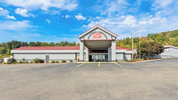 A Red Roof Inn with a red roof and a white facade, featuring a covered entrance and a parking lot. - Red Roof Inn Cambridge, OH (Cambridge)