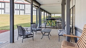 An outdoor patio with seating, a table, and a view of a building with large windows. - Red Roof Inn Cambridge, OH (Cambridge)