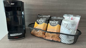 Una cafetera y una cesta con cápsulas de café y espumador de leche.