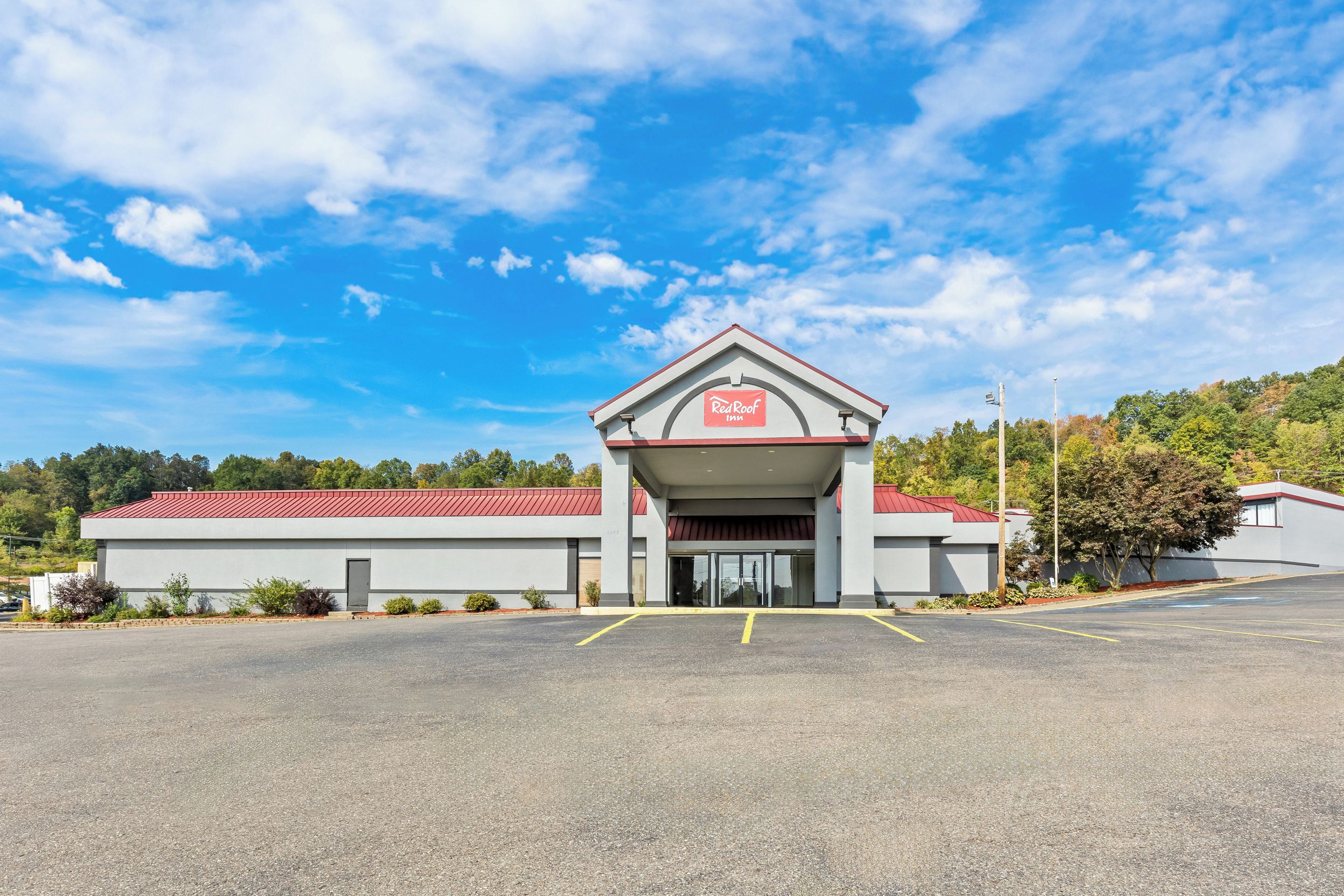A Red Roof Inn with a red roof and a white facade, featuring a covered entrance and a parking lot.
