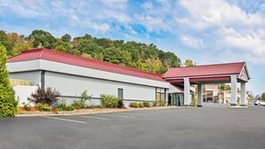 A modern building with a red roof, a covered entrance, and a parking lot. - Red Roof Inn Cambridge, OH (Cambridge)