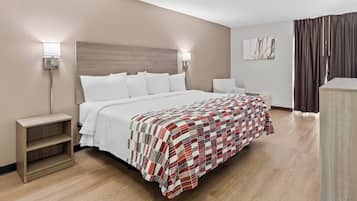 Habitación de hotel con cama, mesitas de noche, sillón, escritorio y una obra de arte colgada en la pared.