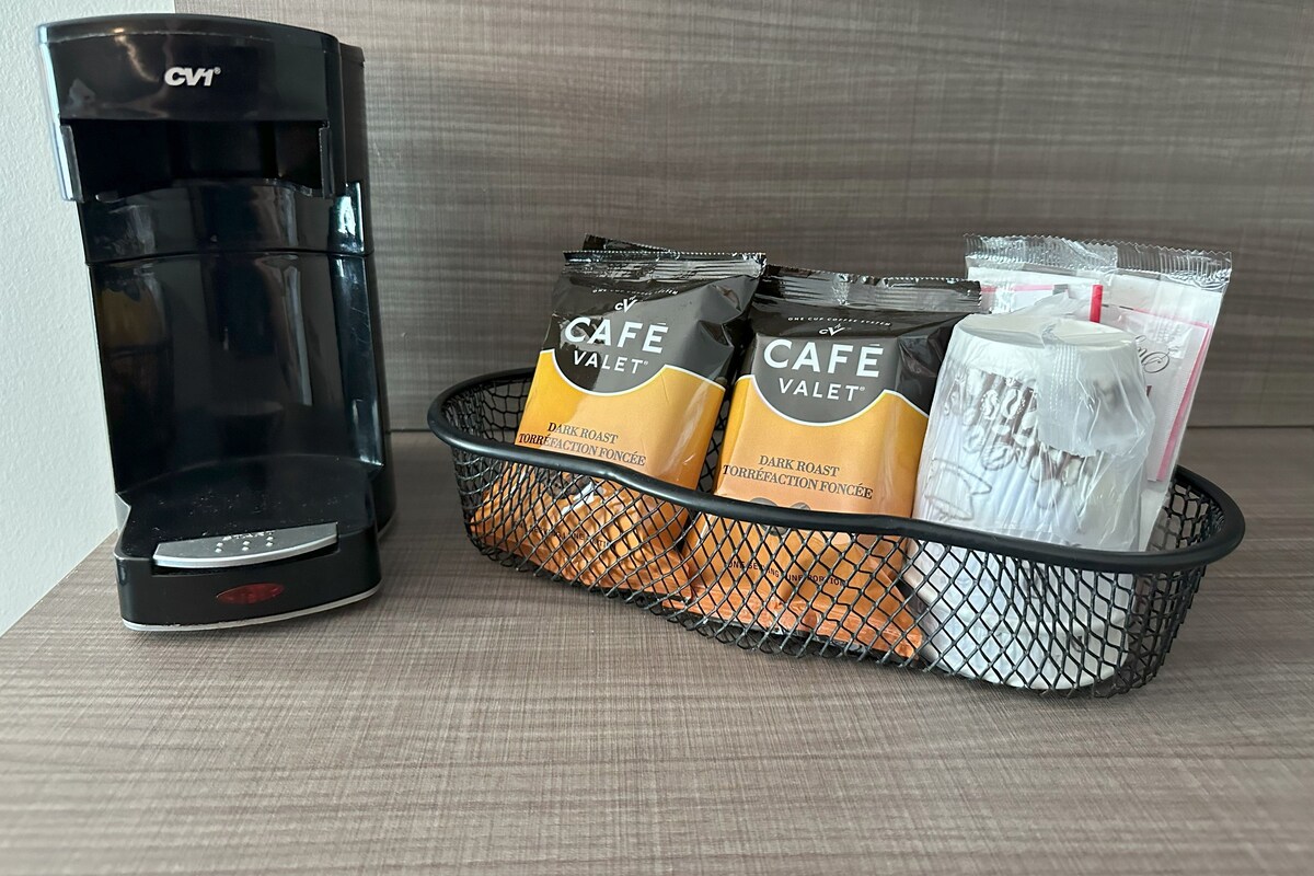 Eine Kaffeemaschine und ein Korb mit Kaffeekapseln und einem Milchaufschäumer.