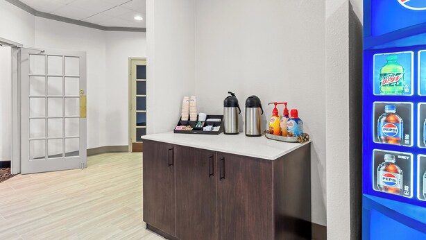 A reception area with a counter, coffee maker, and beverage dispensers. - Red Roof Inn Cambridge, OH (Cambridge)
